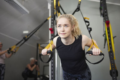 Young woman leaning on gymnastics rings at health club