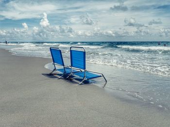 Chairs on beach against sky