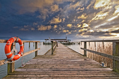 Pier over sea against orange sky