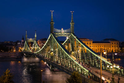 View of suspension bridge over river in city at night