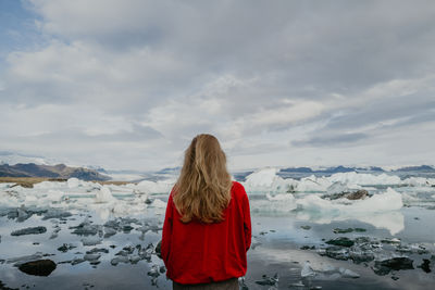 Woman in red jumper standing overlooking jökulsárlón glacier lagoon in iceland