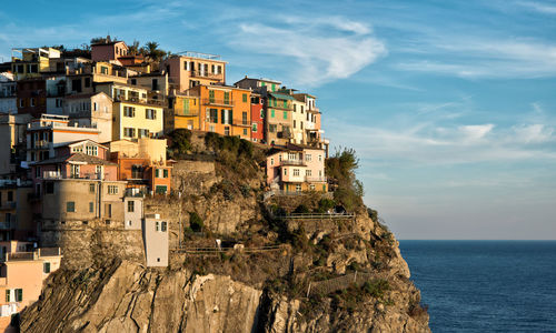 Houses on cliff by sea against sky