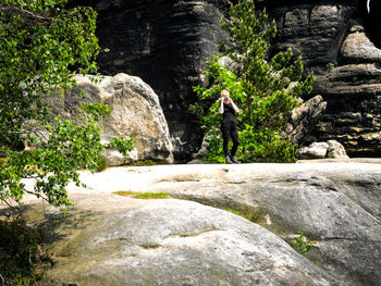 Man standing on rock by waterfall