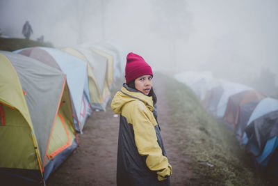 Woman with umbrella standing in foggy weather