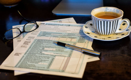 Close-up of coffee cup by documents on table