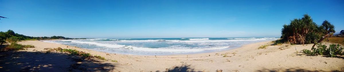 Scenic view of beach against clear blue sky