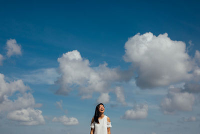 Low angle view of happy woman standing against sky