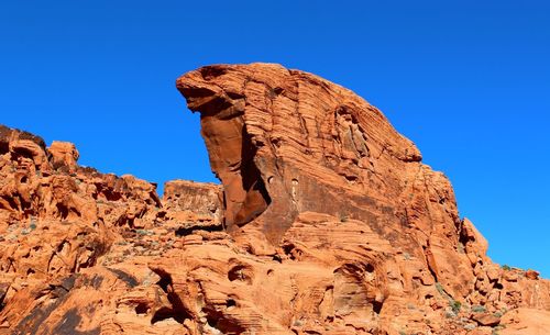 Low angle view of rock formation against clear blue sky