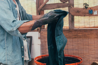 Midsection of man dyeing clothes at workshop