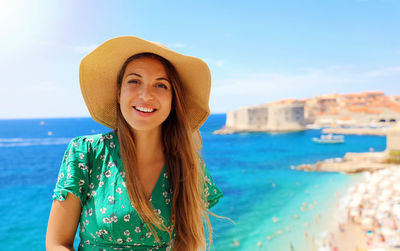 Portrait of smiling young woman standing against sea