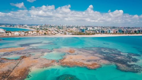 Aerial view of city by sea against sky