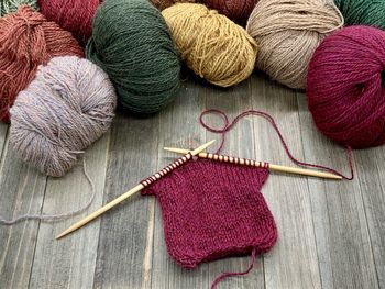 High angle view of multi colored balls of yarn and knitting on wood