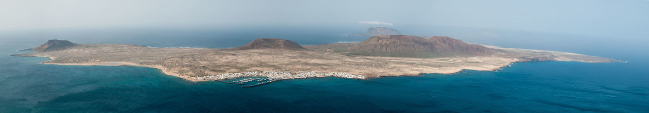 Aerial view of sea by mountain against sky