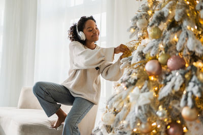 Young woman with christmas tree at home