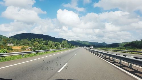 Road by trees against sky