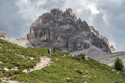 Low angle view of people standing against rock mountain