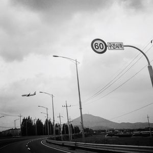 Cars on road against cloudy sky