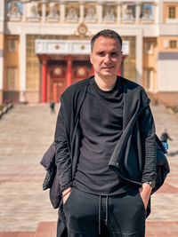 Portrait of man standing against building