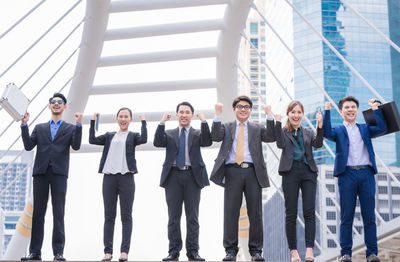 Portrait of smiling businesspeople gesturing against buildings in city