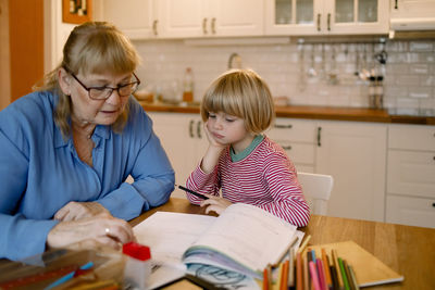 Grandmother assisting grandson in doing homework at home