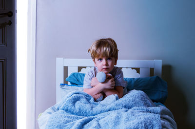 Portrait of cute girl playing with teddy bear on bed at home