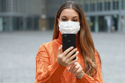 Portrait of woman holding mobile phone standing outdoors