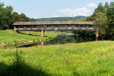 Arch bridge on field against sky