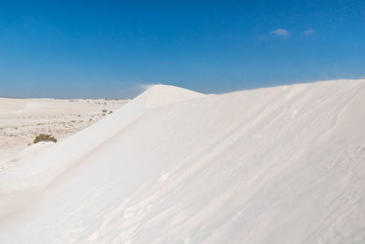 Sand dunes in desert against clear blue sky