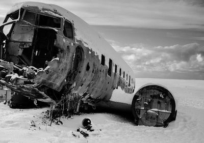 Abandoned airplane on snow against sky