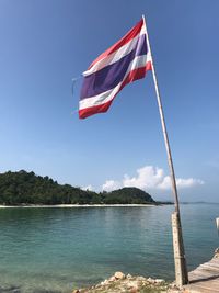 Scenic view of flag by sea against sky