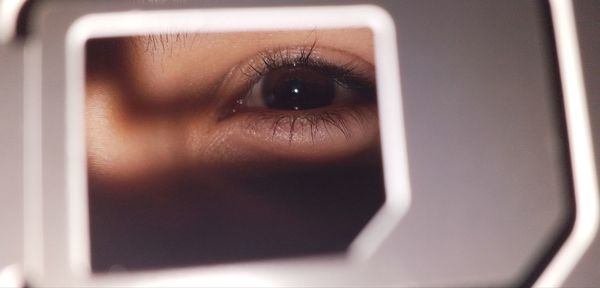 Close-up portrait of woman seen through hole in metal