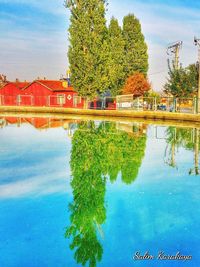 Reflection of trees and swimming pool in lake against sky