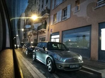 Cars on street by illuminated buildings in city at night