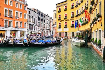 Boats moored in canal amidst buildings in city