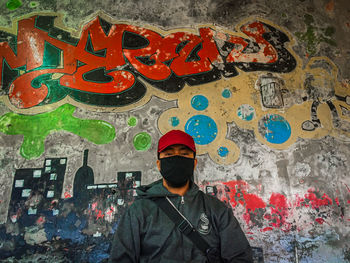 Man standing against graffiti wall