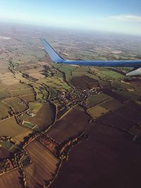 Aerial view of airplane flying over landscape against sky