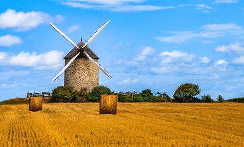 Traditional windmill on field against sky