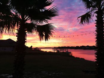 Silhouette palm trees on beach against sky during sunset