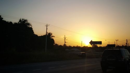 Cars on road against sky during sunset