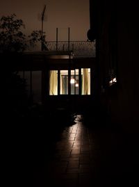 Footpath by silhouette buildings against sky at night