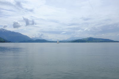 Boat sailing in river against cloudy sky