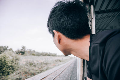 Side view of young man looking through train window