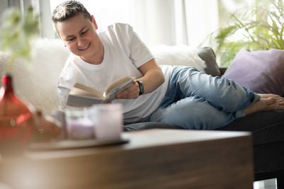 Female friends using mobile phone while sitting on sofa at home