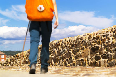 Low section of man walking on land against sky