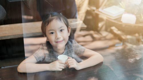 Portrait of smiling girl sitting by table