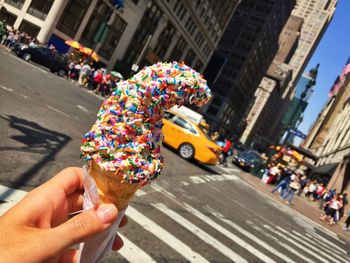 Cropped hand of woman holding ice cream cone on city street