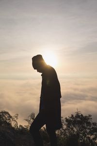 Side view of silhouette man standing against sky during sunset