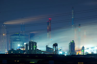 Low angle view of illuminated factory against sky at night