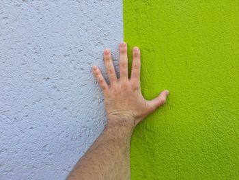 Cropped hand on man touching wall