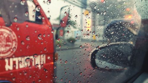 Vehicles on street seen through wet glass window
